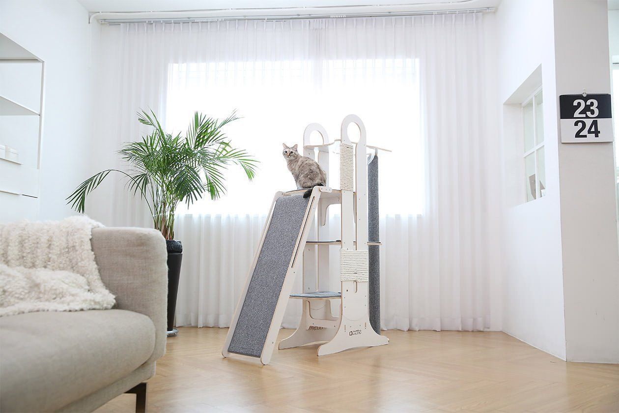 A tall and extravagant modern cat tower from Tuft + Paw with so many little spots for your cat to hang out in.